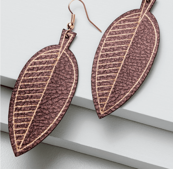 A pair of brown leaf earrings sitting on top of a table.